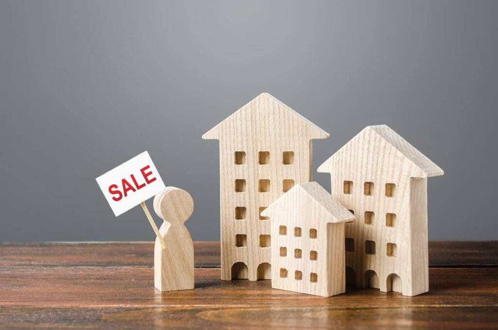 Real estate for sale sign with small wooden houses