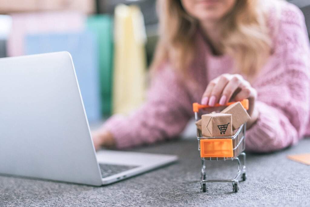 selective focus of toy cart with small paper boxes with woman on background
